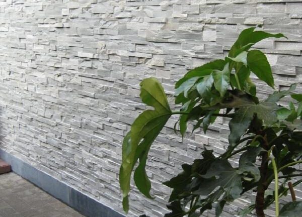 Verwerking steenpanelen - natuursteenstrips Grijs Kwartsiet op een buitenmuur.