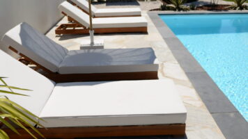 Luxe zwembadterras met Brasil White Flagstones, witte ligbedden, parasol en helderblauw zwembadwater. Alles samengevoegd voor een mediterraans terras met Ibiza vibes
